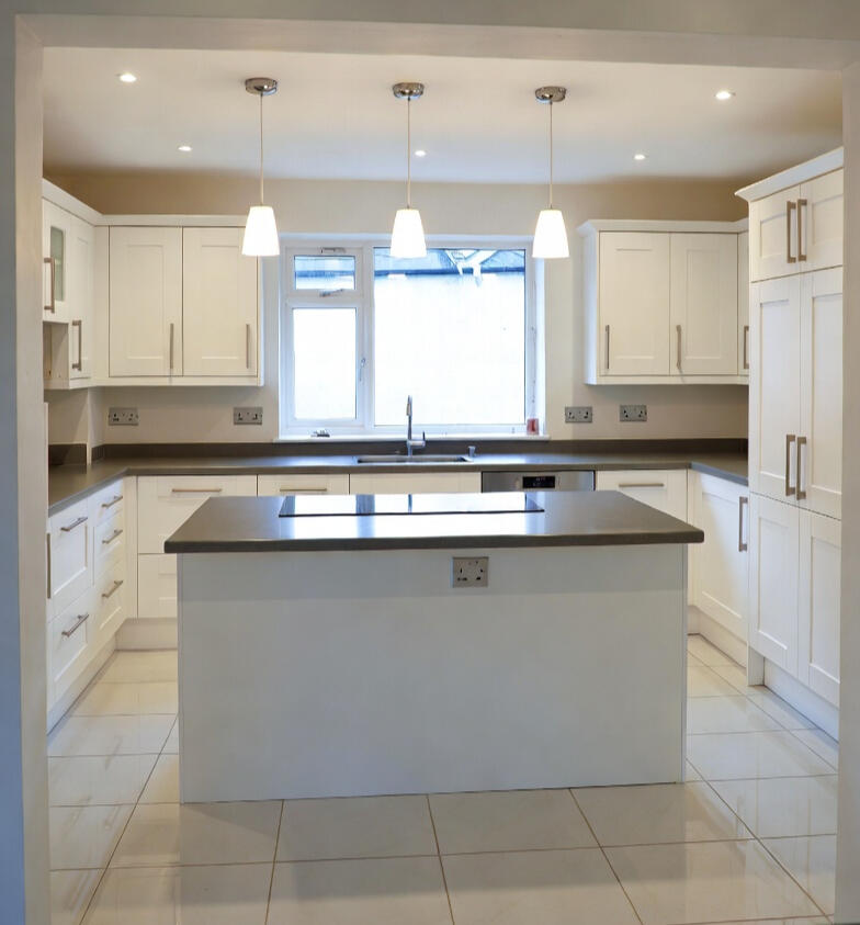 White kitchen with island, pendant lights and a window White kitchen with island, pendant lights and a window